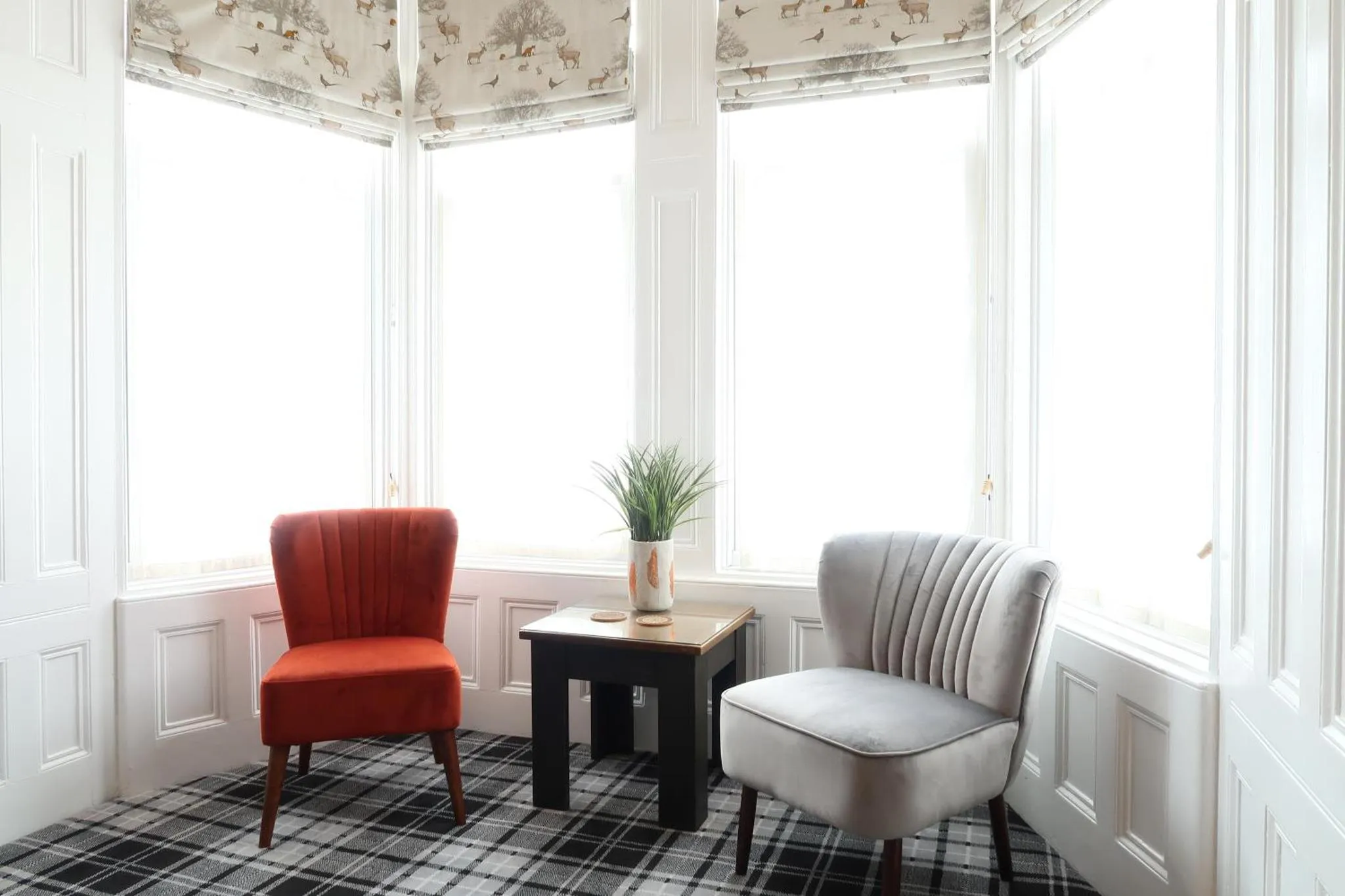 Espace de détente lumineux avec deux fauteuils et une plante.