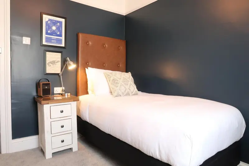 Une chambre avec un lit simple et une décoration murale.