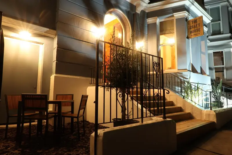 Façade d'un bâtiment éclairée avec un escalier et quelques tables.