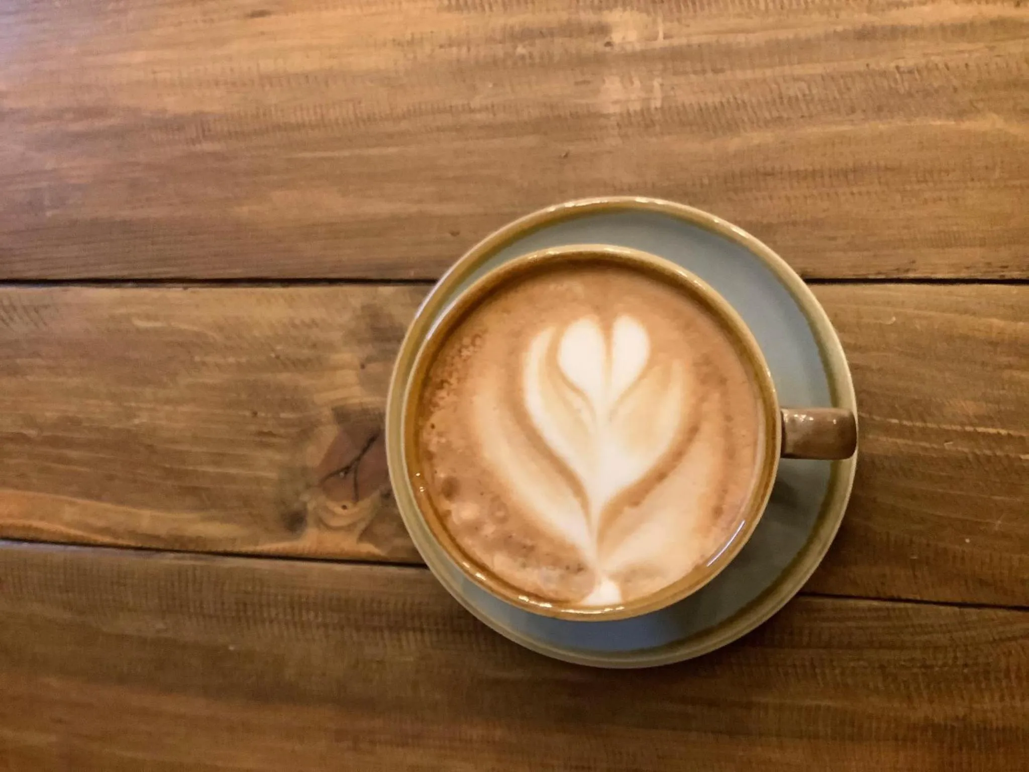 Une tasse de café au lait avec un motif en forme de cœur sur une table en bois.