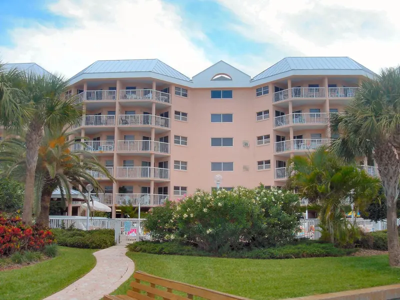 Bâtiment rose à plusieurs étages avec des balcons et une végétation luxuriante.