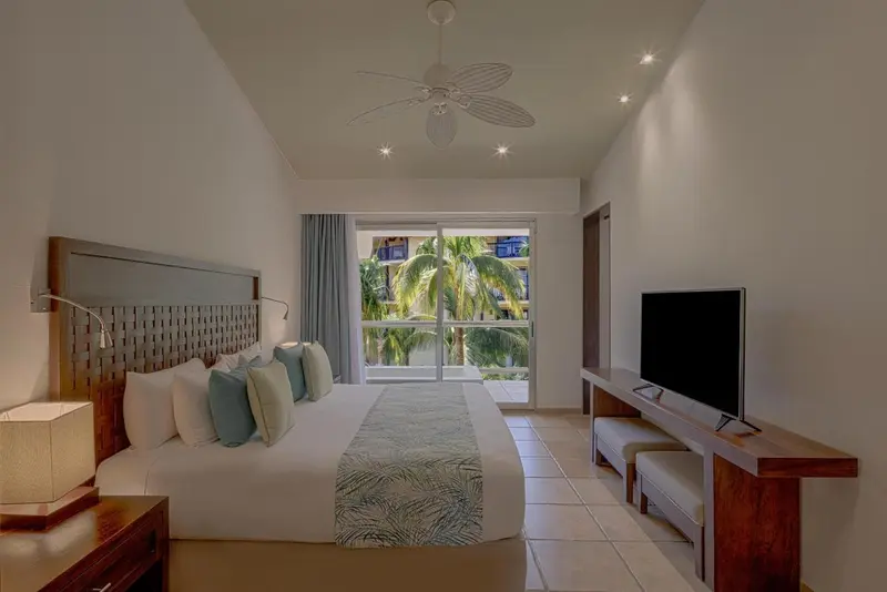 Une chambre lumineuse avec un grand lit et une vue sur la végétation.