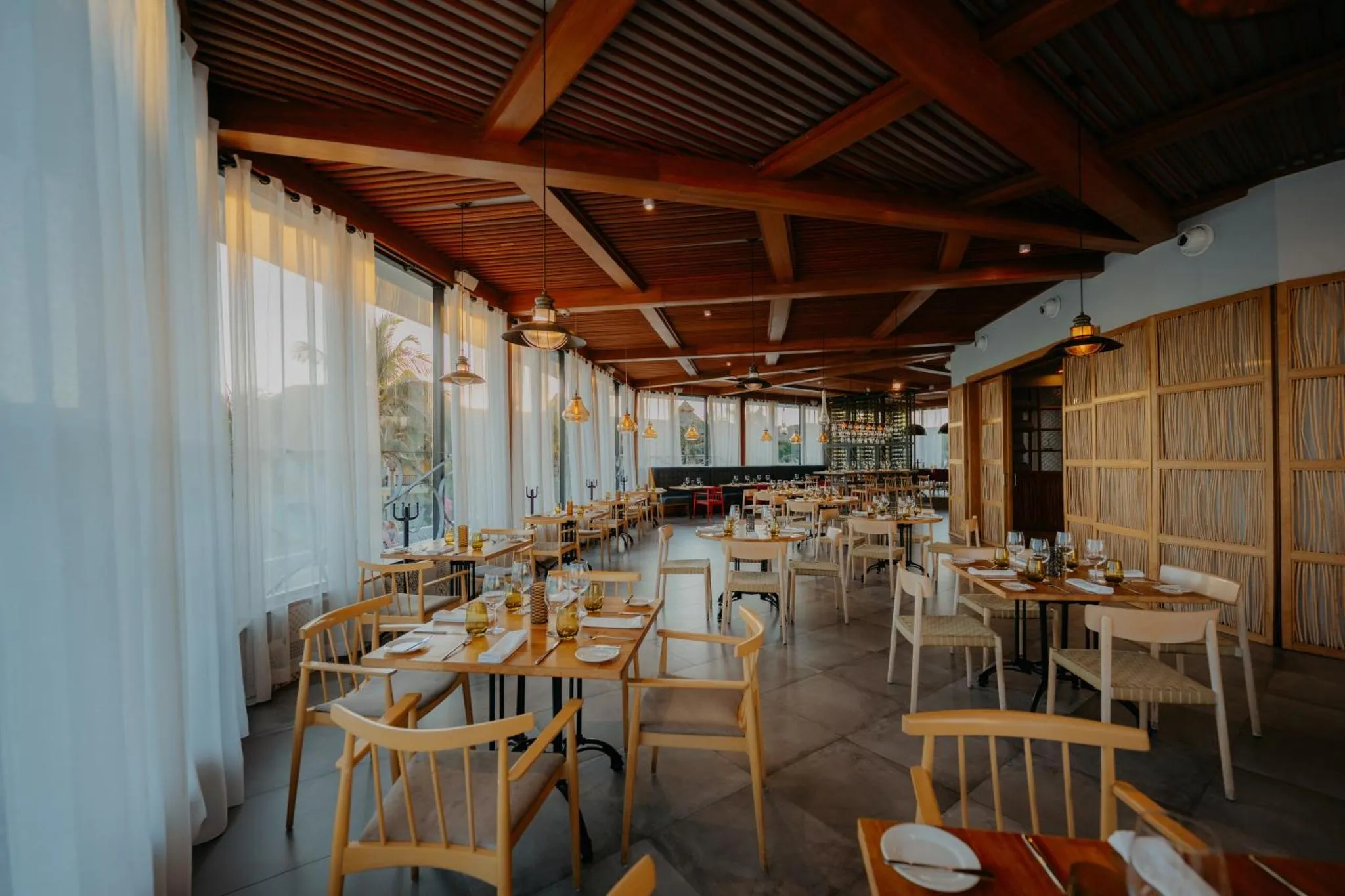 Une salle lumineuse avec des tables dressées pour un repas.