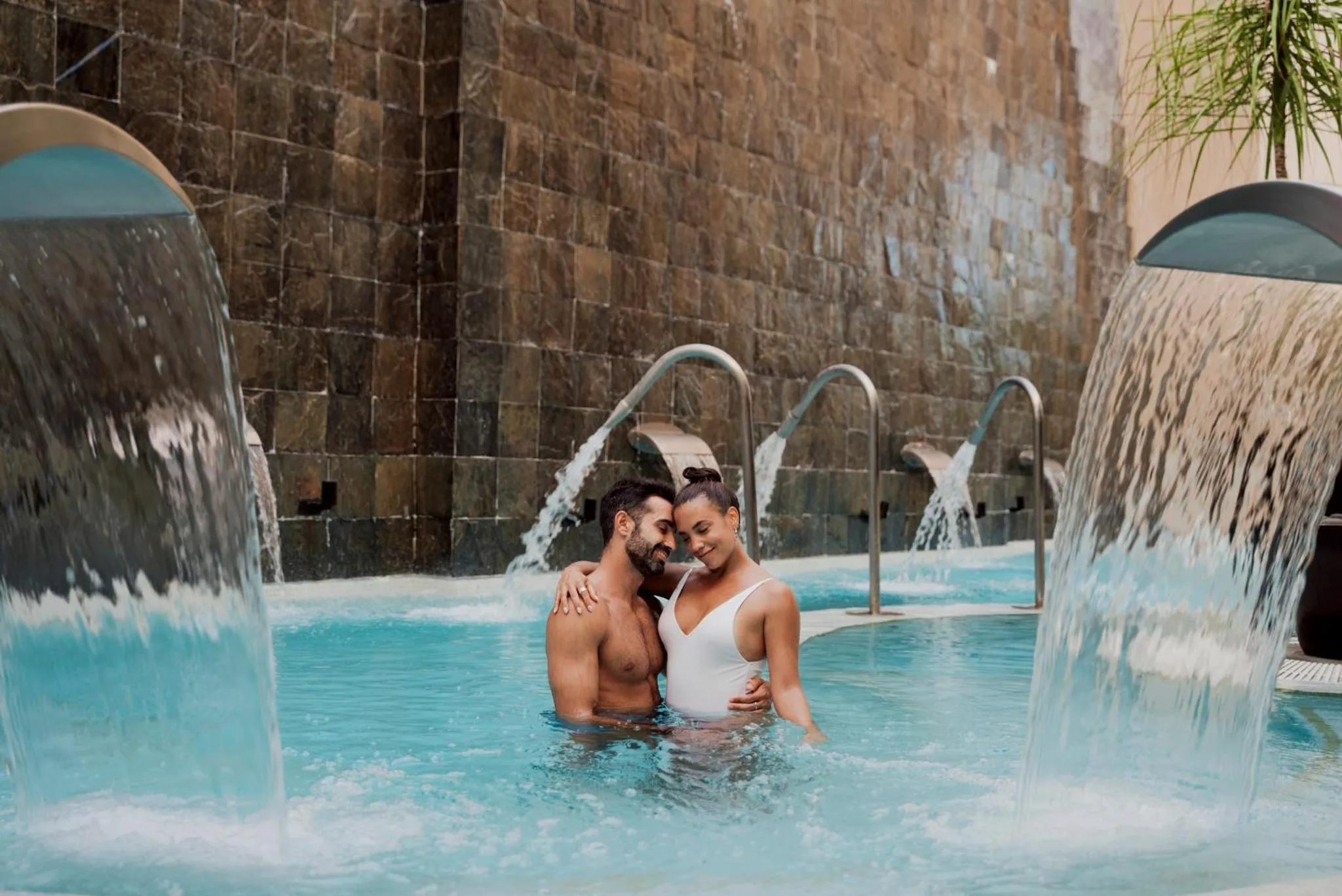 Un couple se détend dans une piscine avec des jets d'eau.