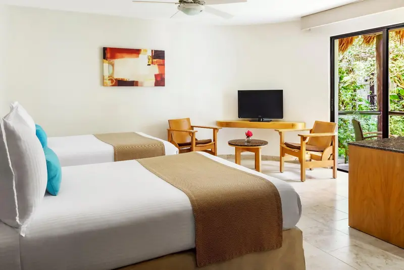 Une chambre lumineuse avec deux lits et un coin salon.
