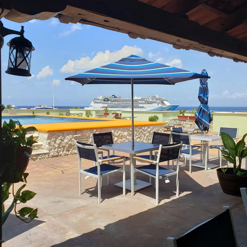 Une table et des chaises sont disposées sur une terrasse ensoleillée avec vue sur la mer.