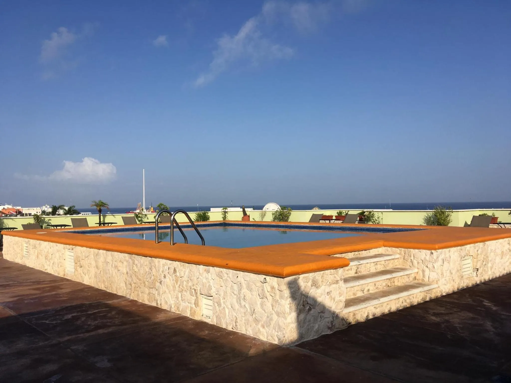 Piscine rectangulaire sur un toit-terrasse ensoleillé avec vue sur la mer.