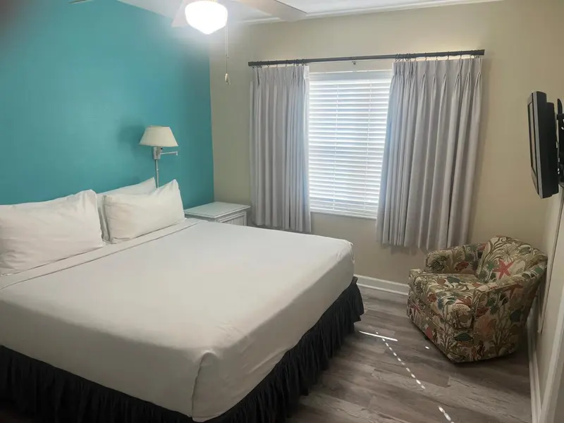 Une chambre lumineuse avec un grand lit et un fauteuil.