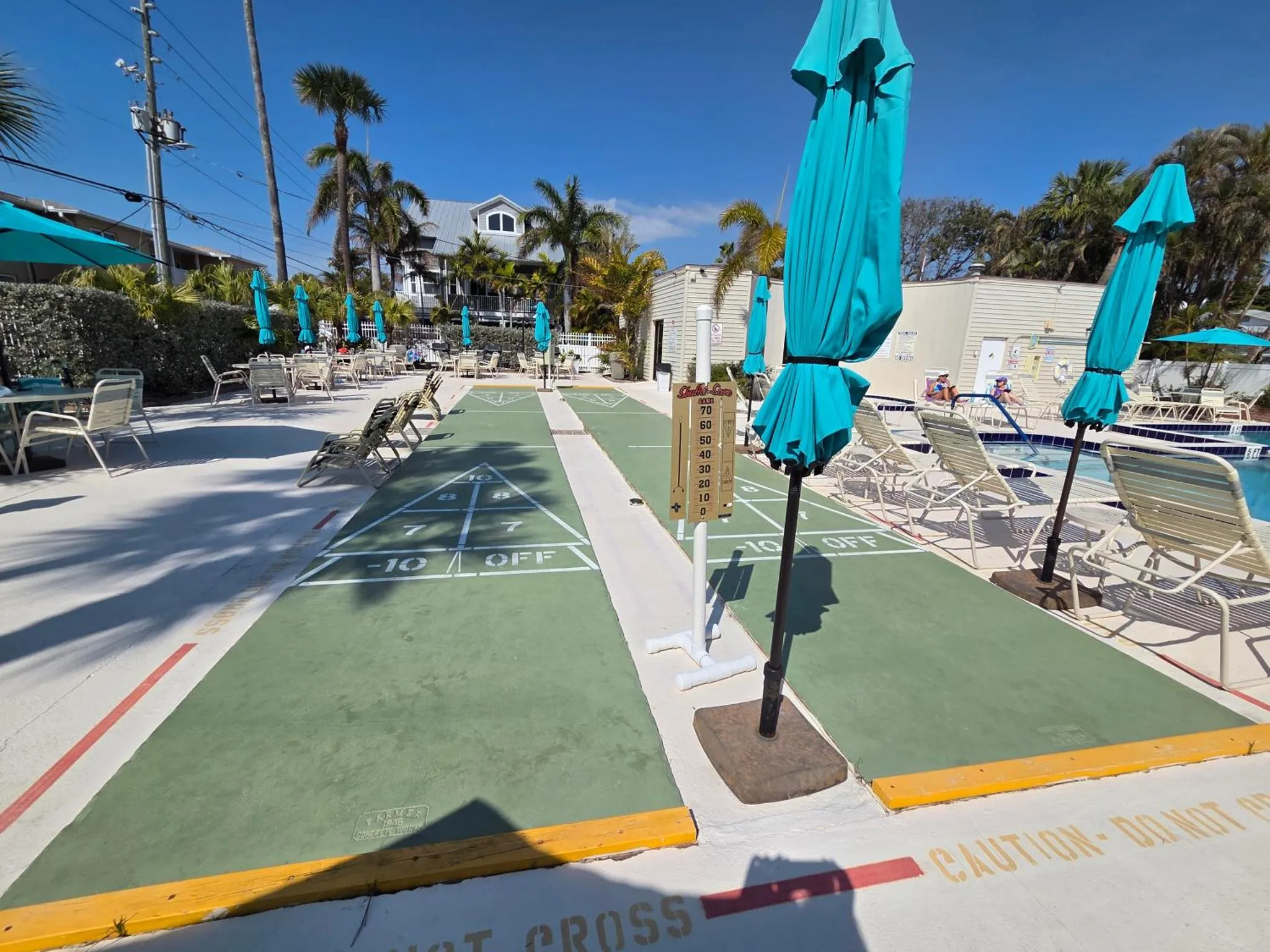 Une terrasse avec des jeux de palets et des transats près d'une piscine.