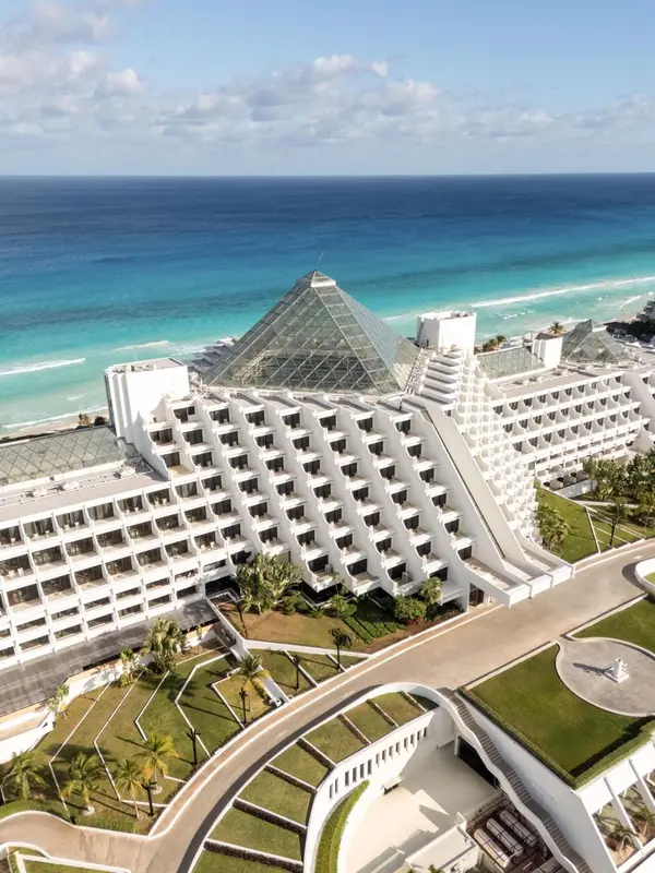 Vue aérienne d'un complexe hôtelier blanc au bord de la mer turquoise.