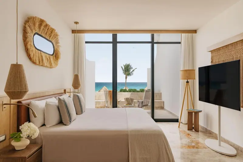 Une chambre lumineuse avec un grand lit et vue sur la mer.