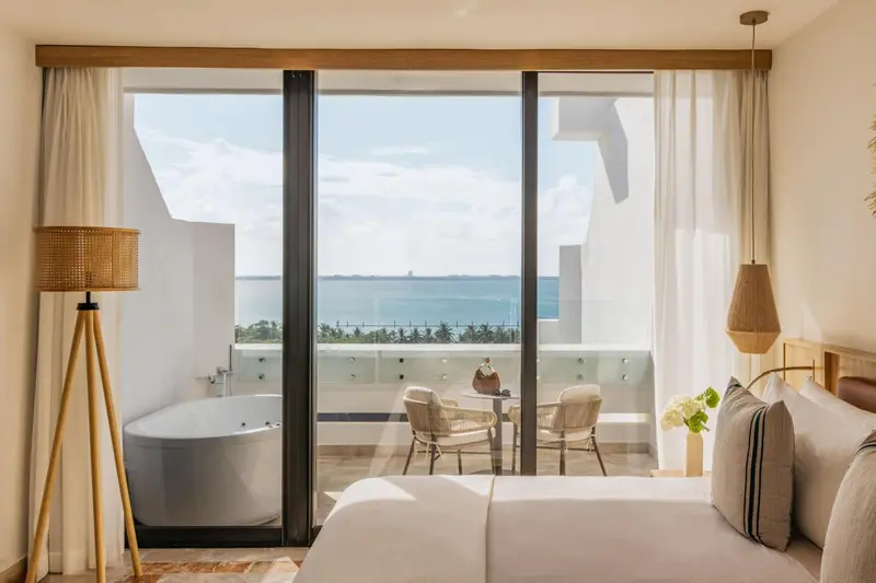 Une chambre lumineuse avec un grand balcon donnant sur la mer.