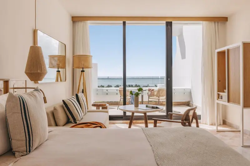 Une chambre lumineuse avec un canapé et un lit donnant sur une vue mer.