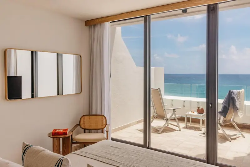 Une chambre lumineuse s'ouvre sur une terrasse avec vue sur la mer.