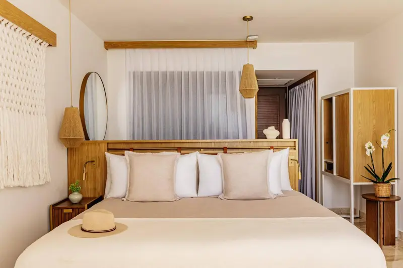 Une chambre lumineuse avec un grand lit recouvert de coussins.