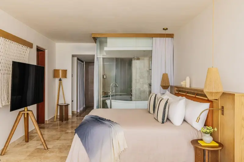 Une chambre lumineuse avec un grand lit et une salle de bain attenante.