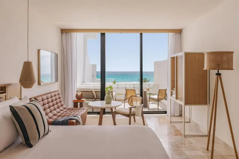 Une chambre lumineuse s'ouvre sur une vue mer via de grandes baies vitrées.