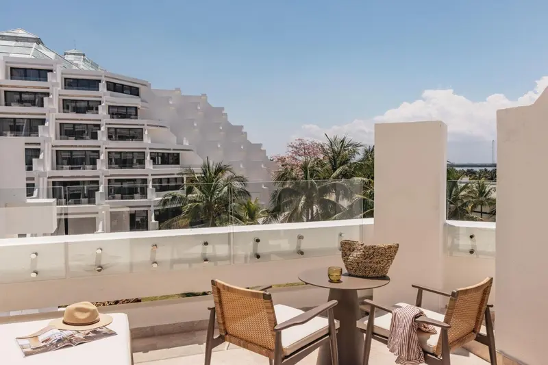 Terrasse avec mobilier d'extérieur et vue sur un bâtiment blanc.