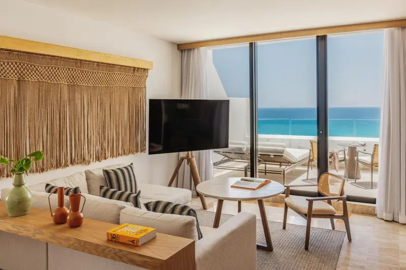 Espace de vie lumineux avec canapé, table basse et vue sur la mer.