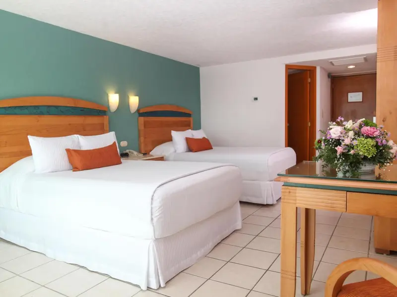 Une chambre lumineuse avec deux lits simples et une composition florale sur une table.