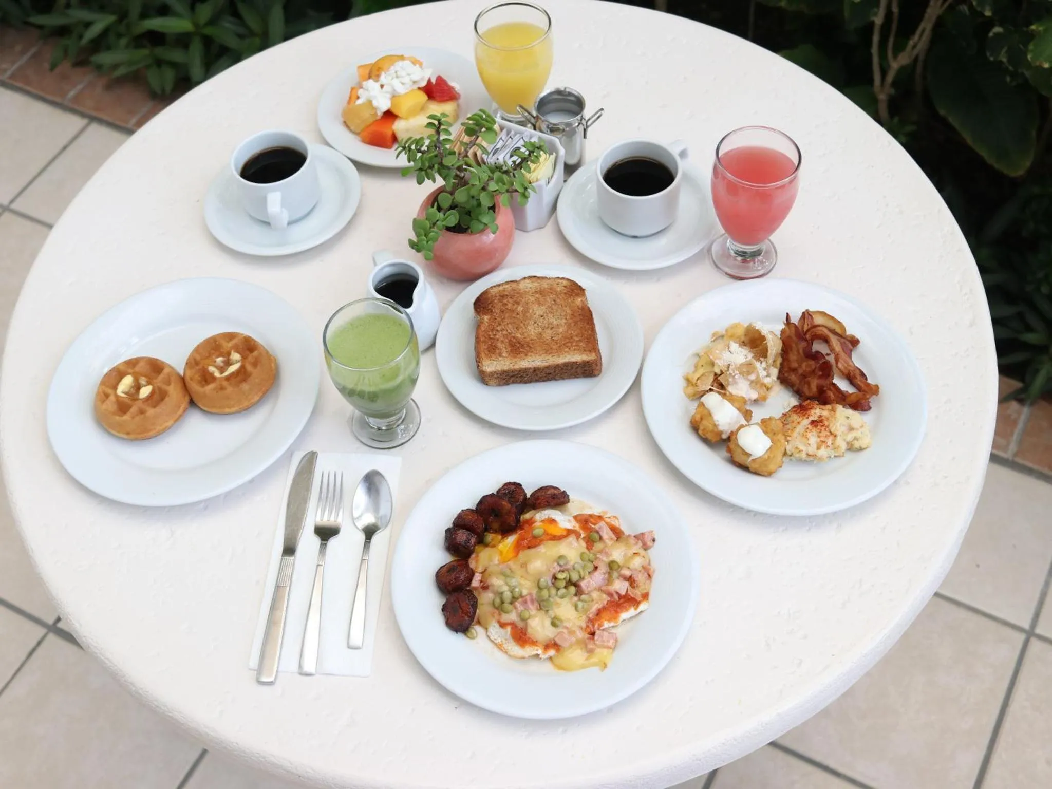 Une table ronde est dressée avec un assortiment de plats et de boissons pour le petit-déjeuner.