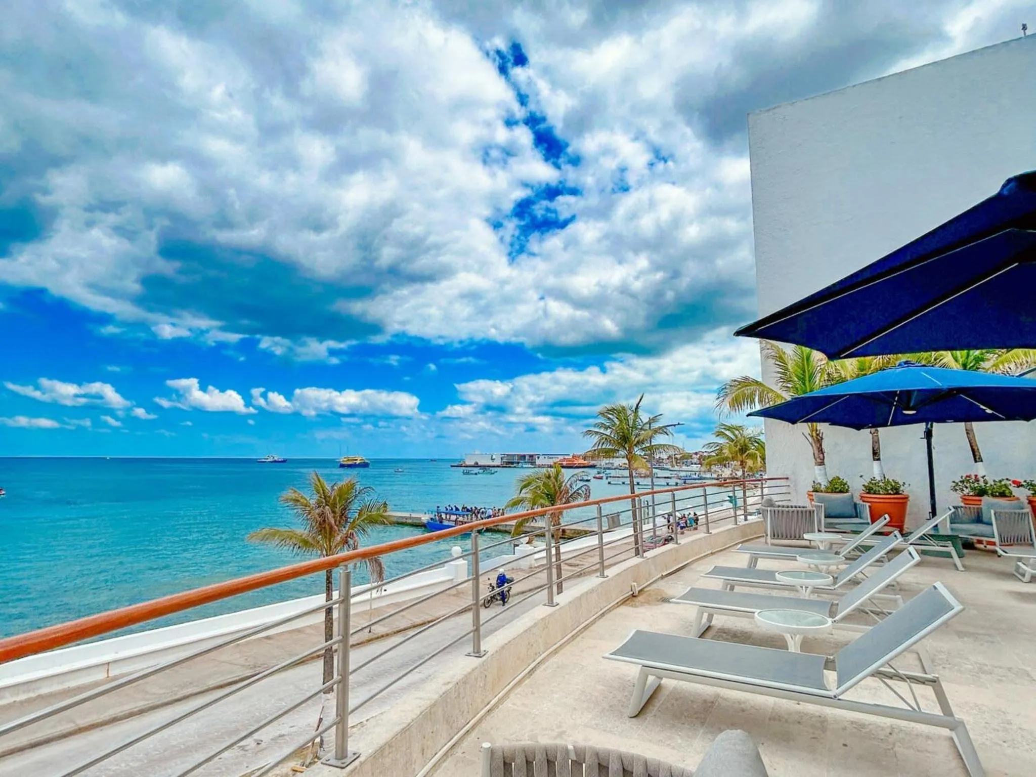 Terrasse ensoleillée avec transats et vue sur la mer turquoise.