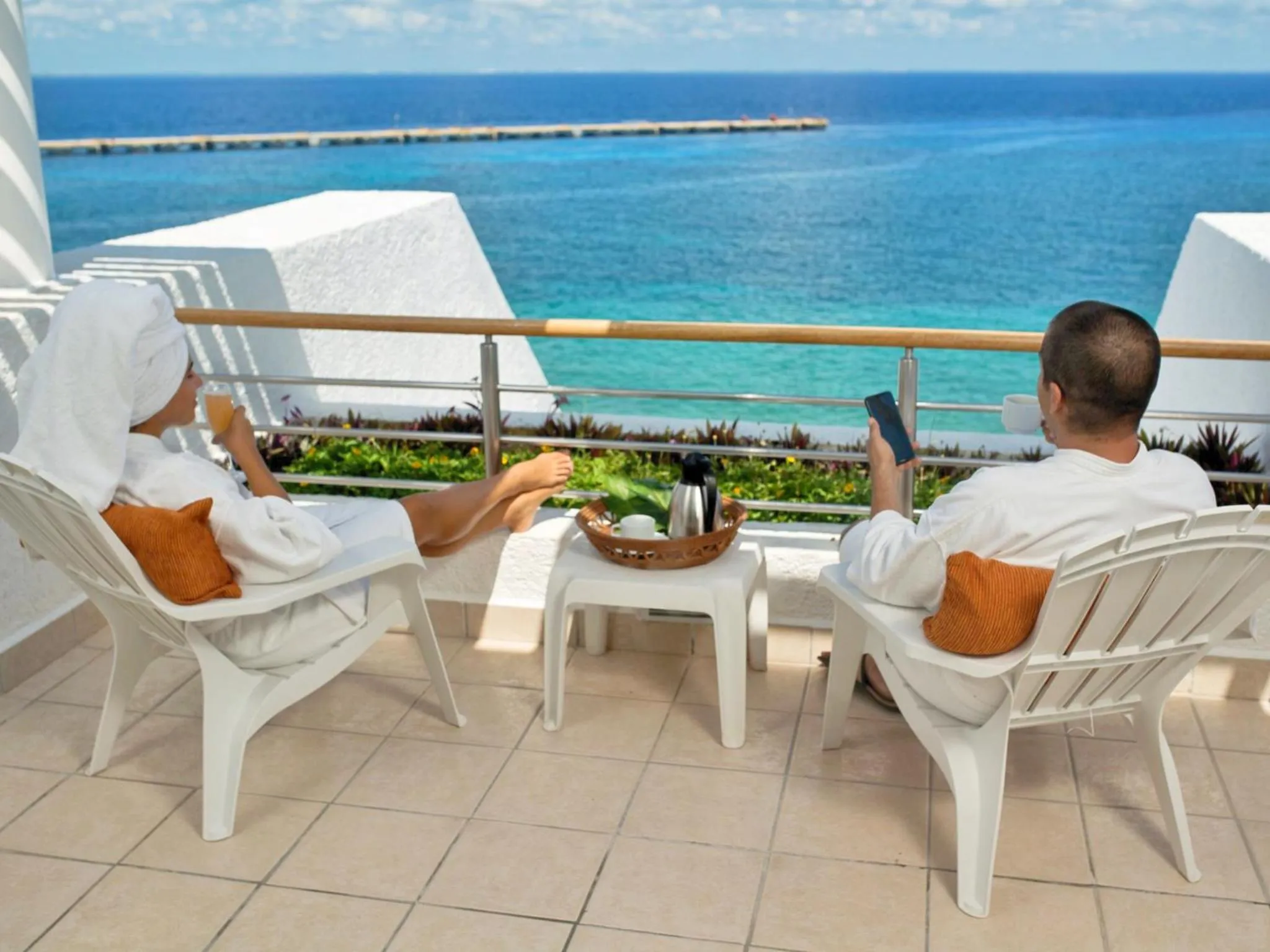 Deux personnes se détendent sur une terrasse avec vue sur la mer.