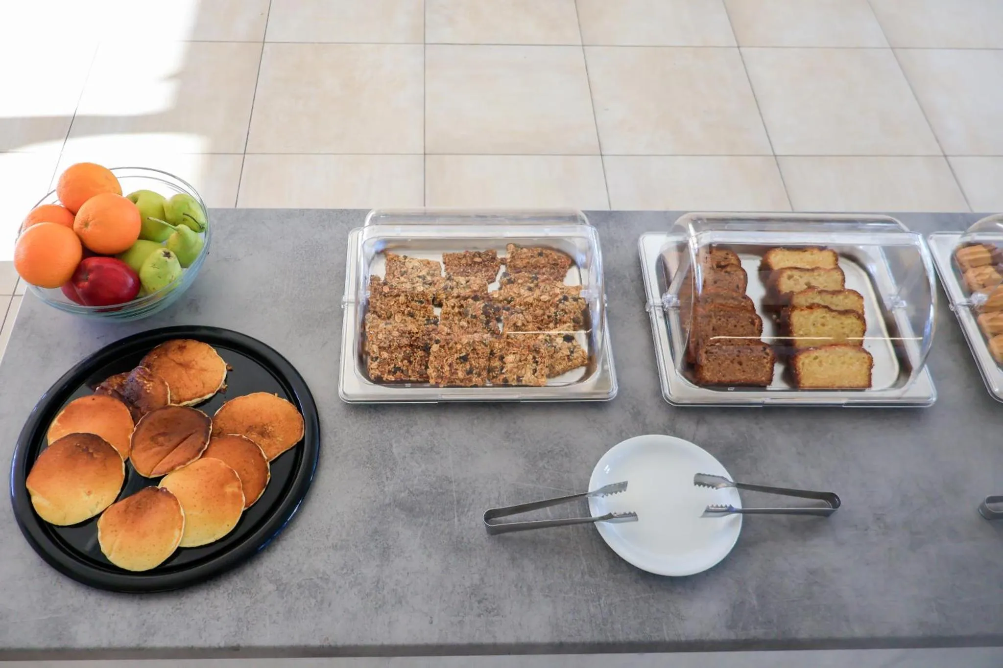 Présentation de viennoiseries et de fruits frais sur un buffet.