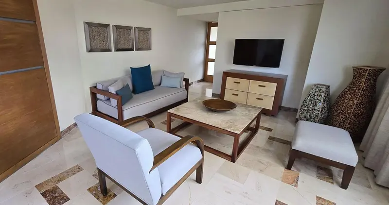 Un salon clair avec canapés, fauteuils et une table basse.