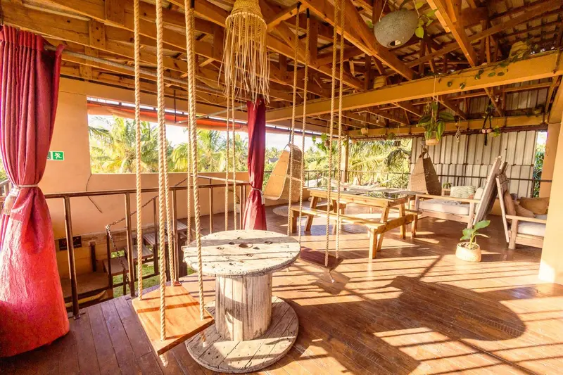 Espace de détente extérieur avec tables et balançoires en bois.