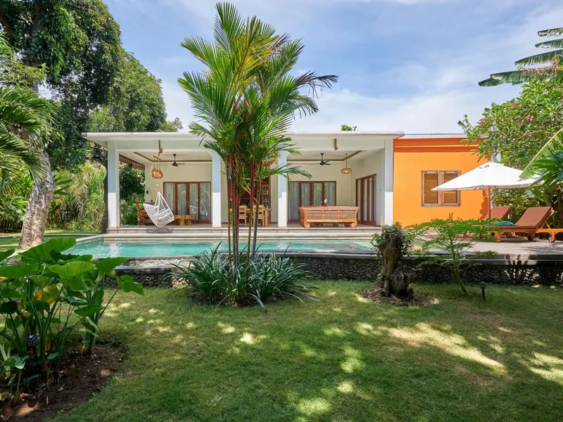Une piscine devant une maison colorée avec une végétation luxuriante.
