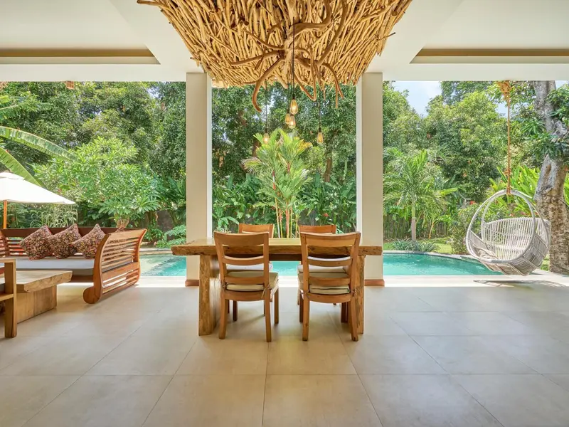 Espace de repas extérieur avec table et chaises près d'une piscine.