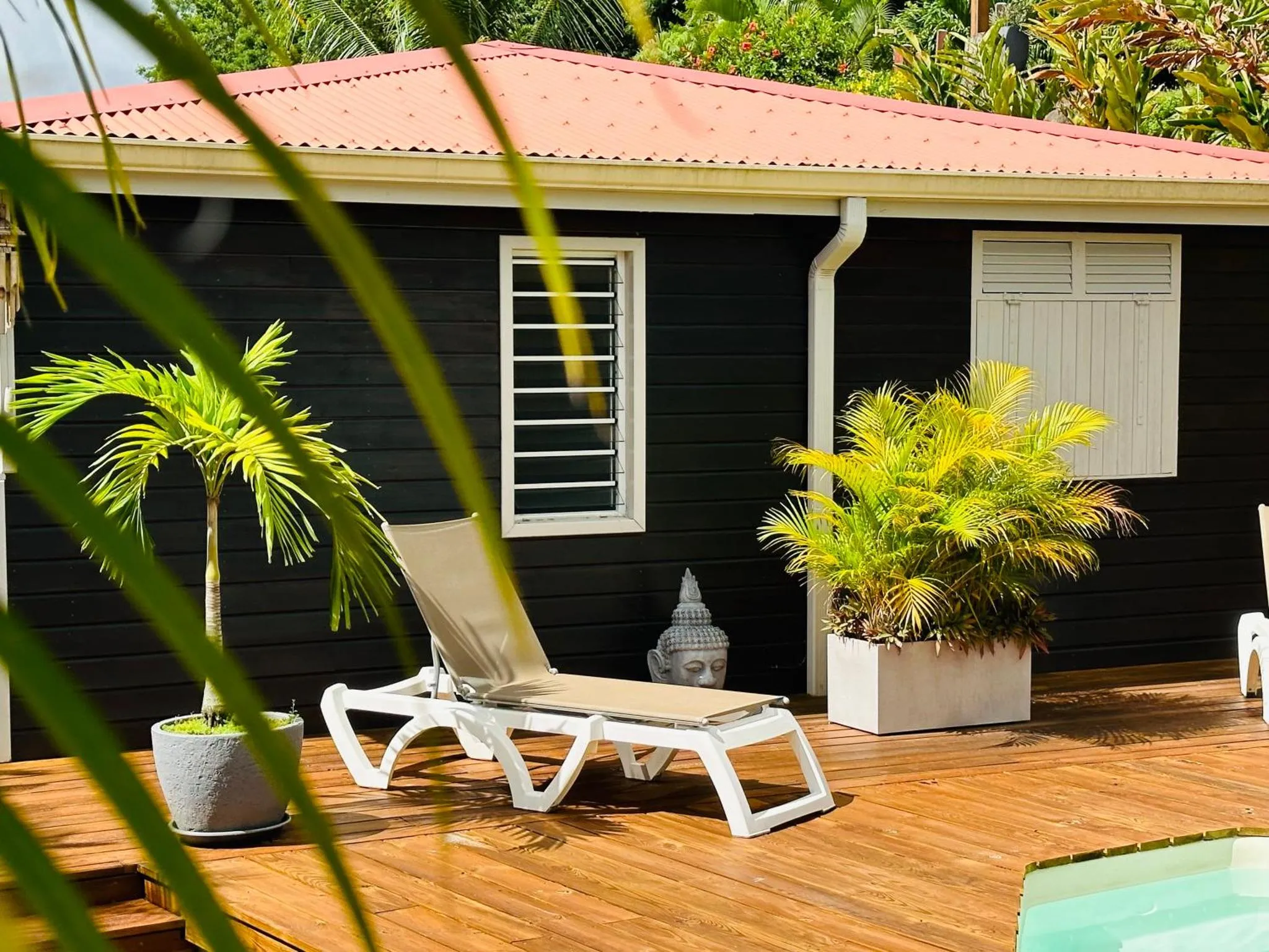 Transat blanc sur une terrasse en bois devant un bâtiment sombre.