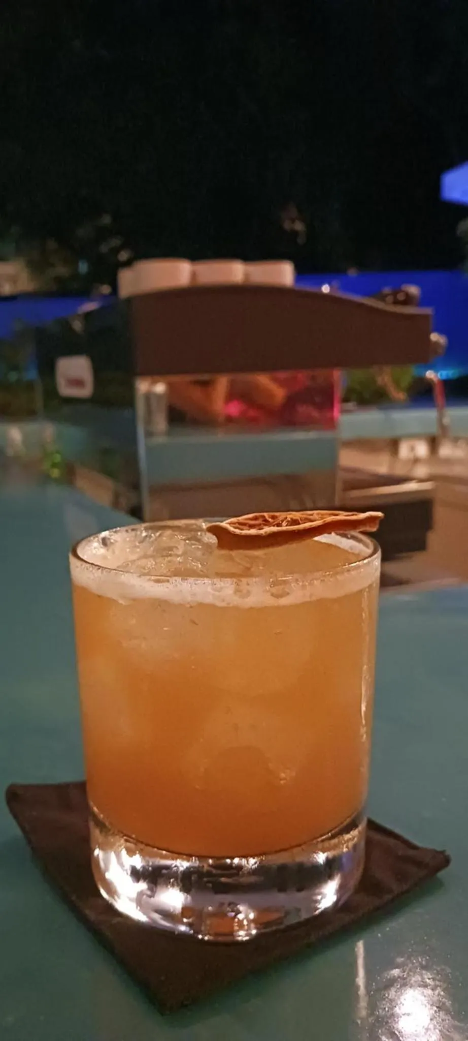 Un verre de cocktail est pose sur une table en bord de piscine.
