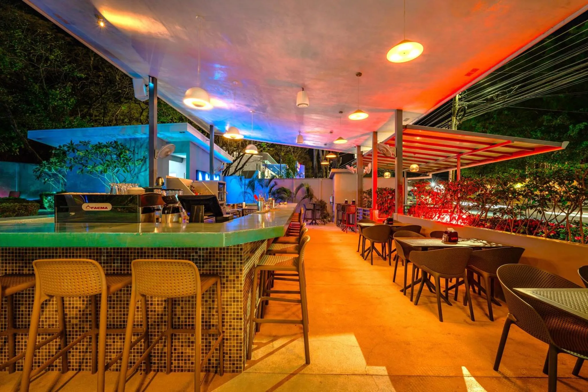Un bar lumineux avec des tabourets et des tables en extérieur.