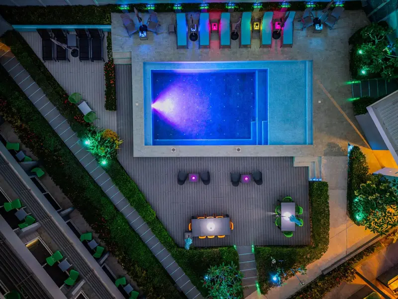 Vue aérienne d'une piscine rectangulaire entourée d'un solarium et de végétation.