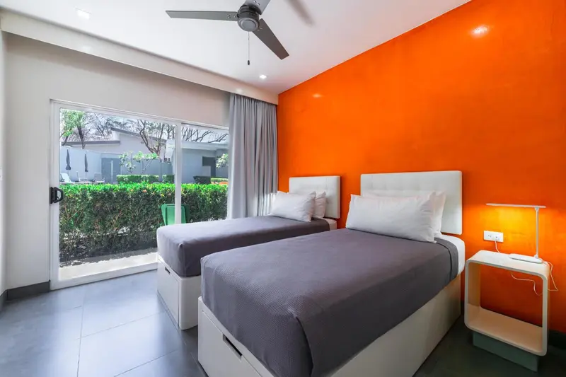 Une chambre lumineuse avec deux lits simples et un accès à une terrasse.