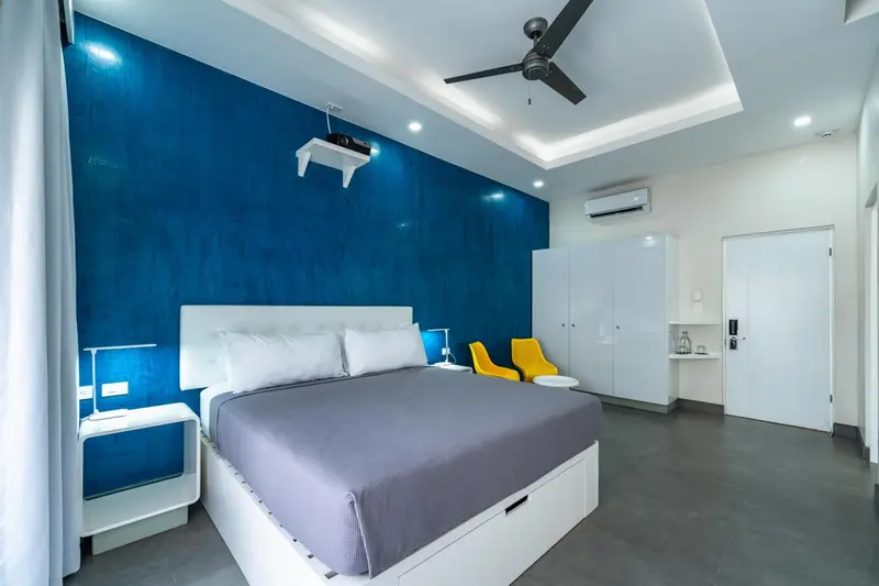 Une chambre lumineuse avec un grand lit et un mur bleu.