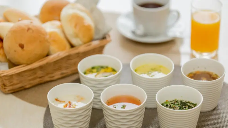 Une table présente des viennoiseries, des confitures et des jus de fruits.