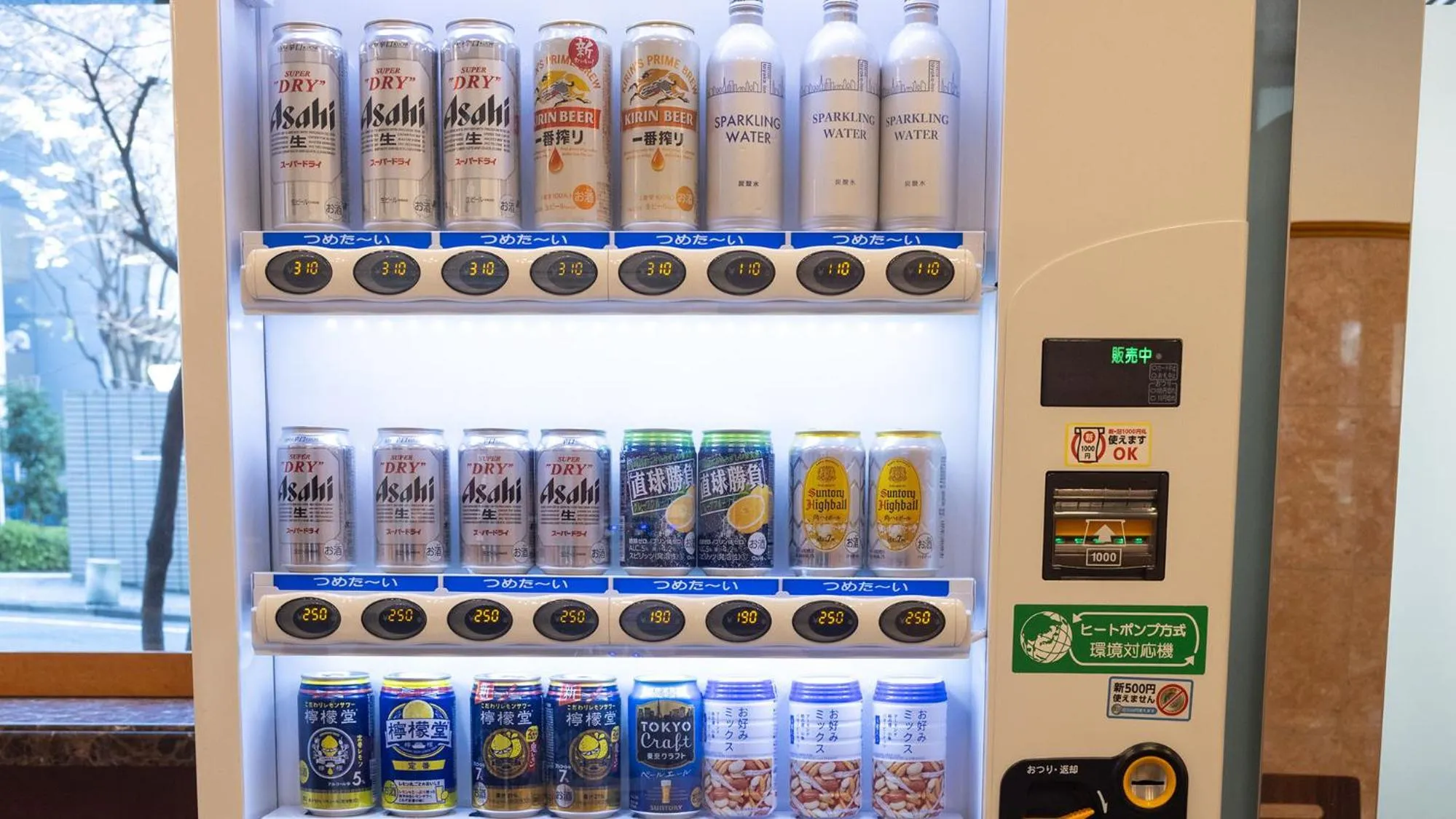 Un distributeur automatique propose une variété de boissons en canettes et en bouteilles.