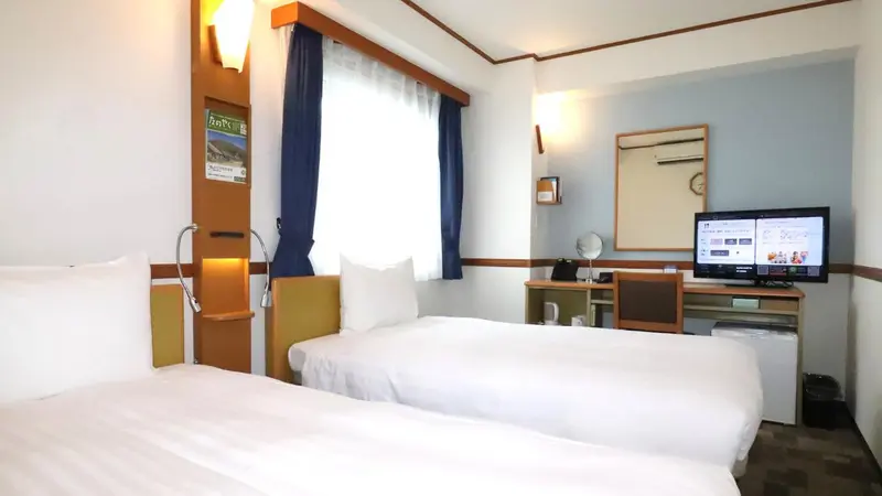 Une chambre d'hôtel avec deux lits simples et un téléviseur.