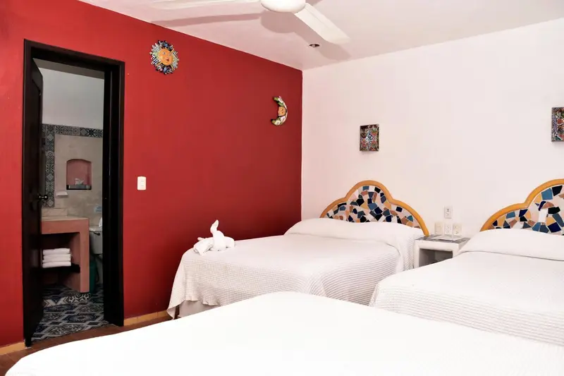 Une chambre lumineuse avec deux lits décorés de mosaïques et un accès à une salle de bain.