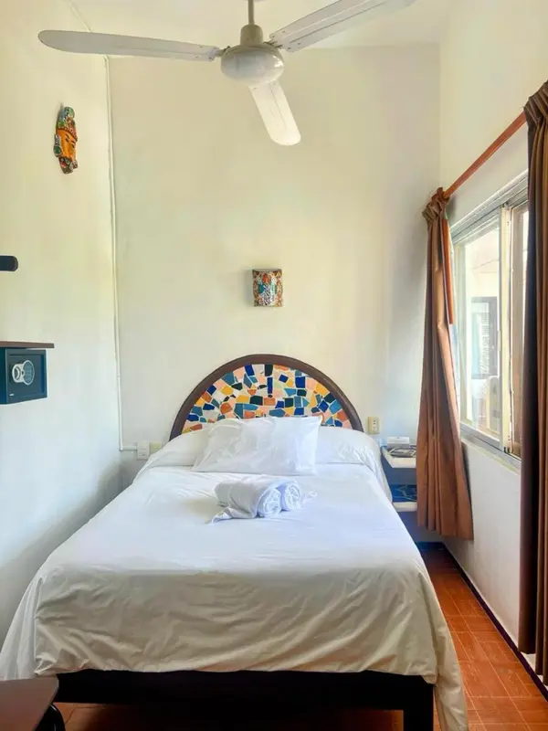 Une chambre lumineuse avec un lit fait et des décorations murales colorées.
