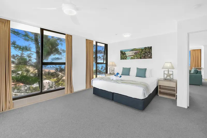 Chambre lumineuse avec un grand lit et une vue sur la mer.