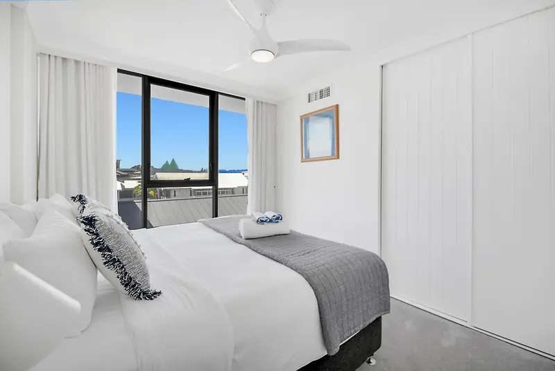 Une chambre lumineuse avec un grand lit et une vue sur la ville.