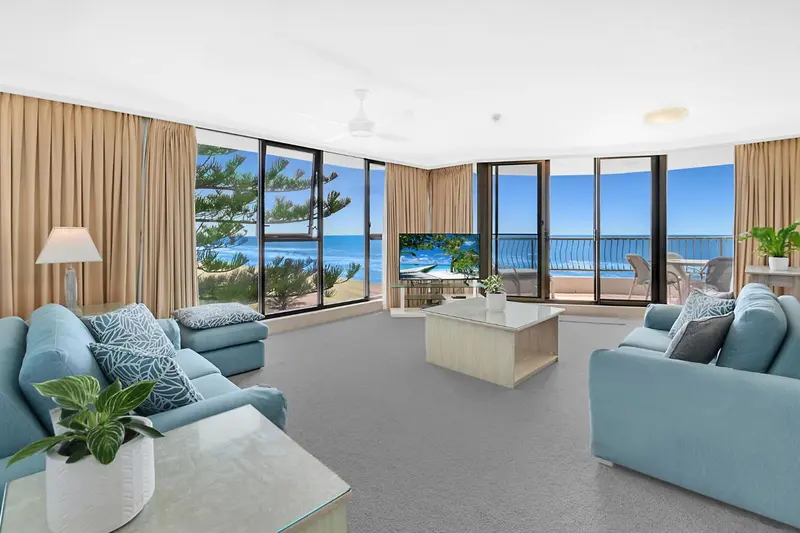 Un salon lumineux avec vue sur la mer par de grandes baies vitrées.