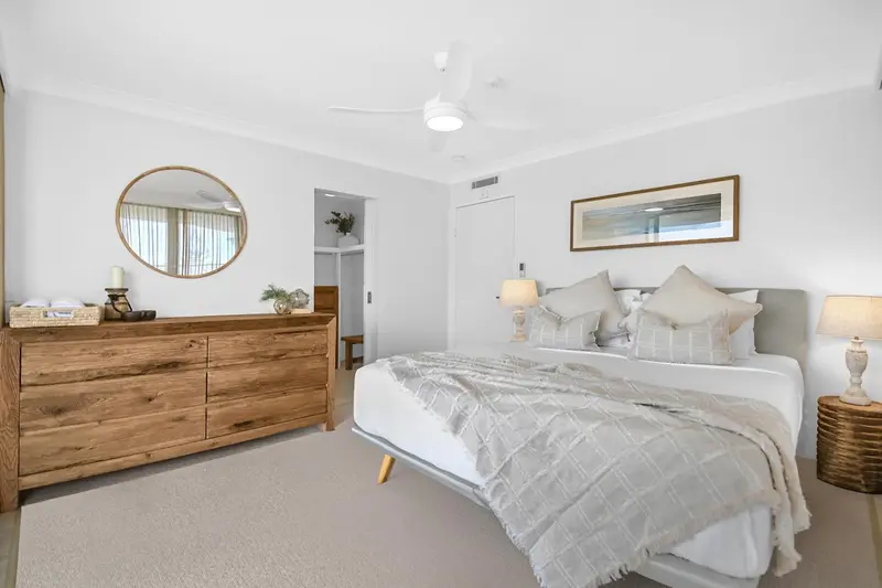 Une chambre lumineuse avec un grand lit et une commode en bois.