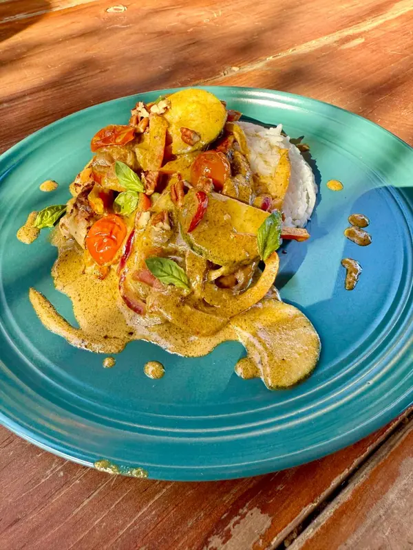 Assiette de riz et de curry décorée de légumes et d'herbes fraîches.