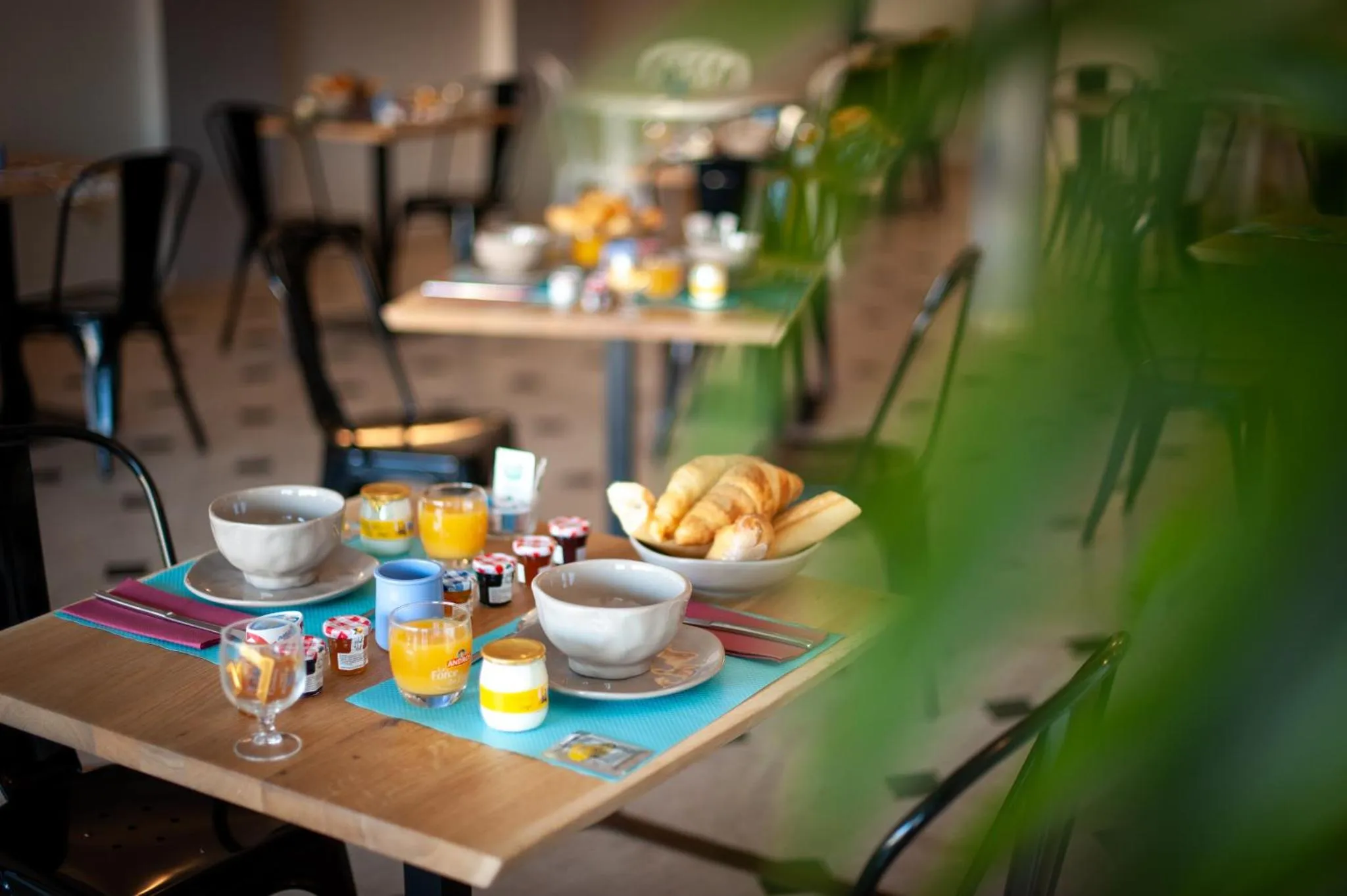 Une table est dressée pour le petit-déjeuner avec des viennoiseries et des boissons.
