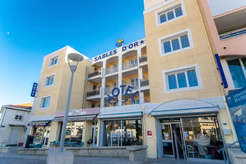 Façade d'un bâtiment jaune à plusieurs étages avec des balcons et des enseignes.